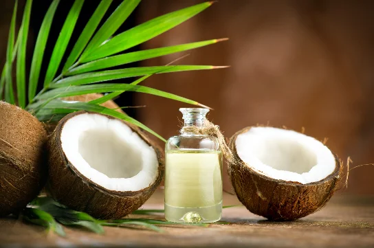 Split coconuts beside a bottle of pure coconut oil