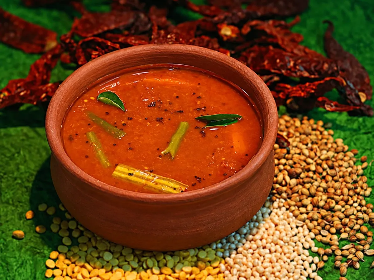 Sambar in an earthen clay pot with dried red chillies, coriander seeds and dals